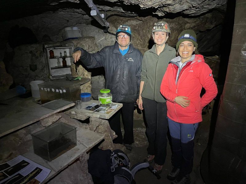 Tre ricercatrici con casco accanto alle vasche e ai banchi di un laboratorio ricavato in grotta